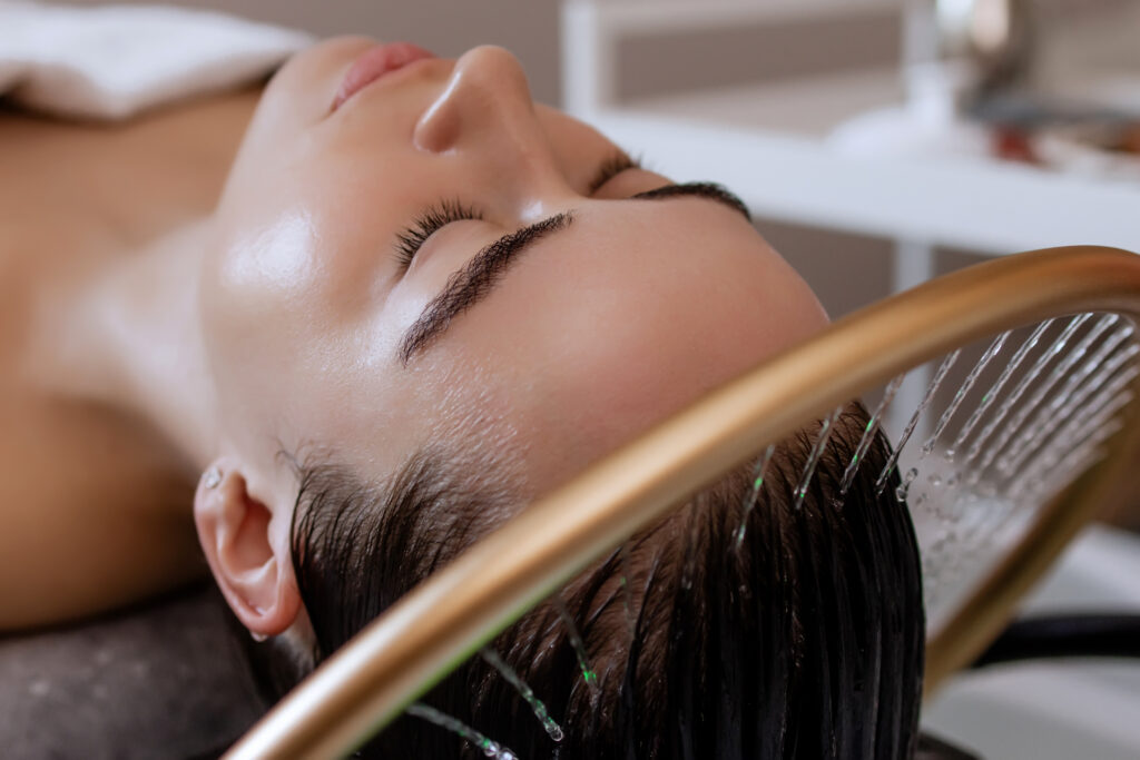 Woman enjoying a relaxing Japanese head spa treatment with a gold waterfall scalp rinse gently cleansing her hair.