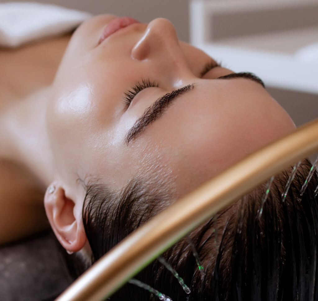 Woman enjoying a relaxing Japanese head spa treatment with a gold waterfall scalp rinse gently cleansing her hair.