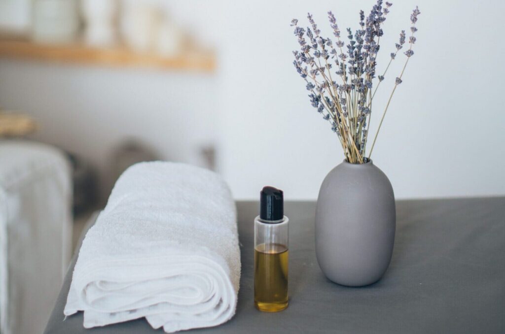 Luxury spa essentials featuring a soft white towel, massage oil, and dried lavender flowers, creating a calming atmosphere for Japanese-inspired head spa treatments.