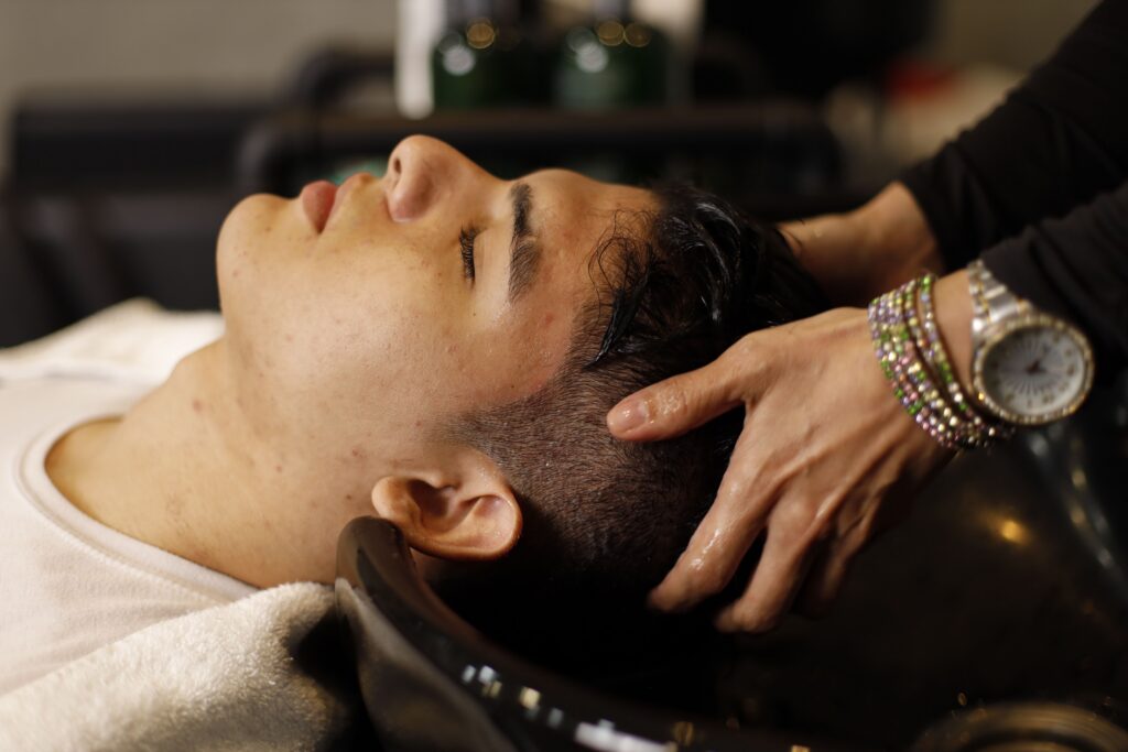 Man receiving a relaxing Japanese head spa treatment with a therapeutic scalp massage and gentle hair cleansing for scalp wellness and tension relief.