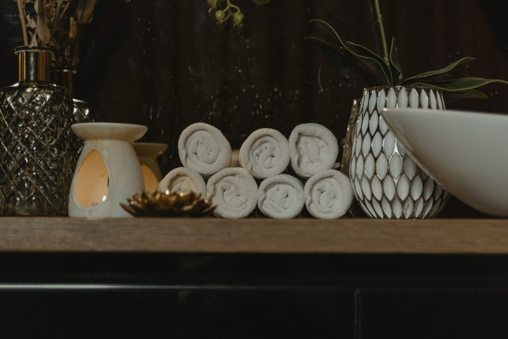 Luxury spa setting with rolled white towels, aromatherapy diffuser, decorative plants, and calming wellness essentials for a Japanese head spa experience.